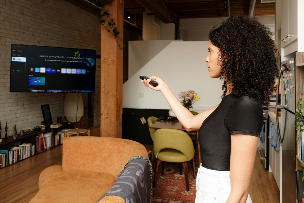Mulher mexendo na televisão com controle remoto