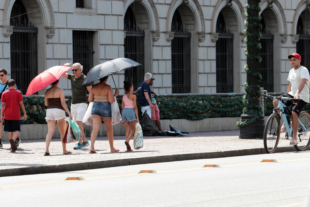 Pessoas com sombrinhas para se proteger do sol